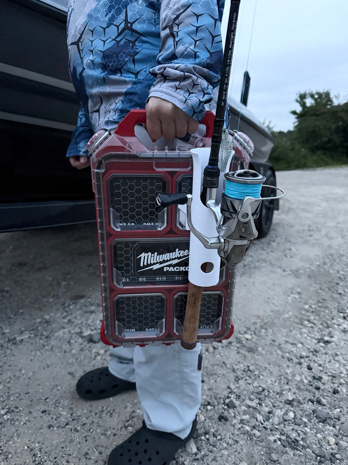 Packout-compatible fishing rod holder mounted to tackle organizer with spinning rod